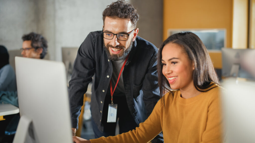 Lecturer Helps Scholar with Project, Advising on Their Work. Teacher Giving Lesson to Diverse Multiethnic Group of Female and Male Students in College Room, Teaching New Academic Skills on a Computer.
